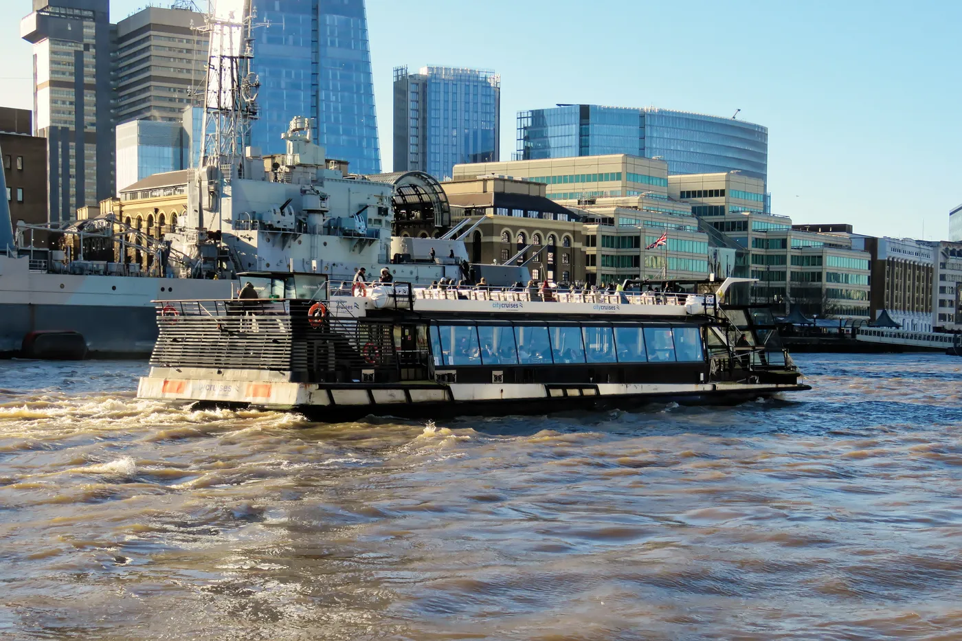 Sightseeing boat on the Thames passing HMS Belfast